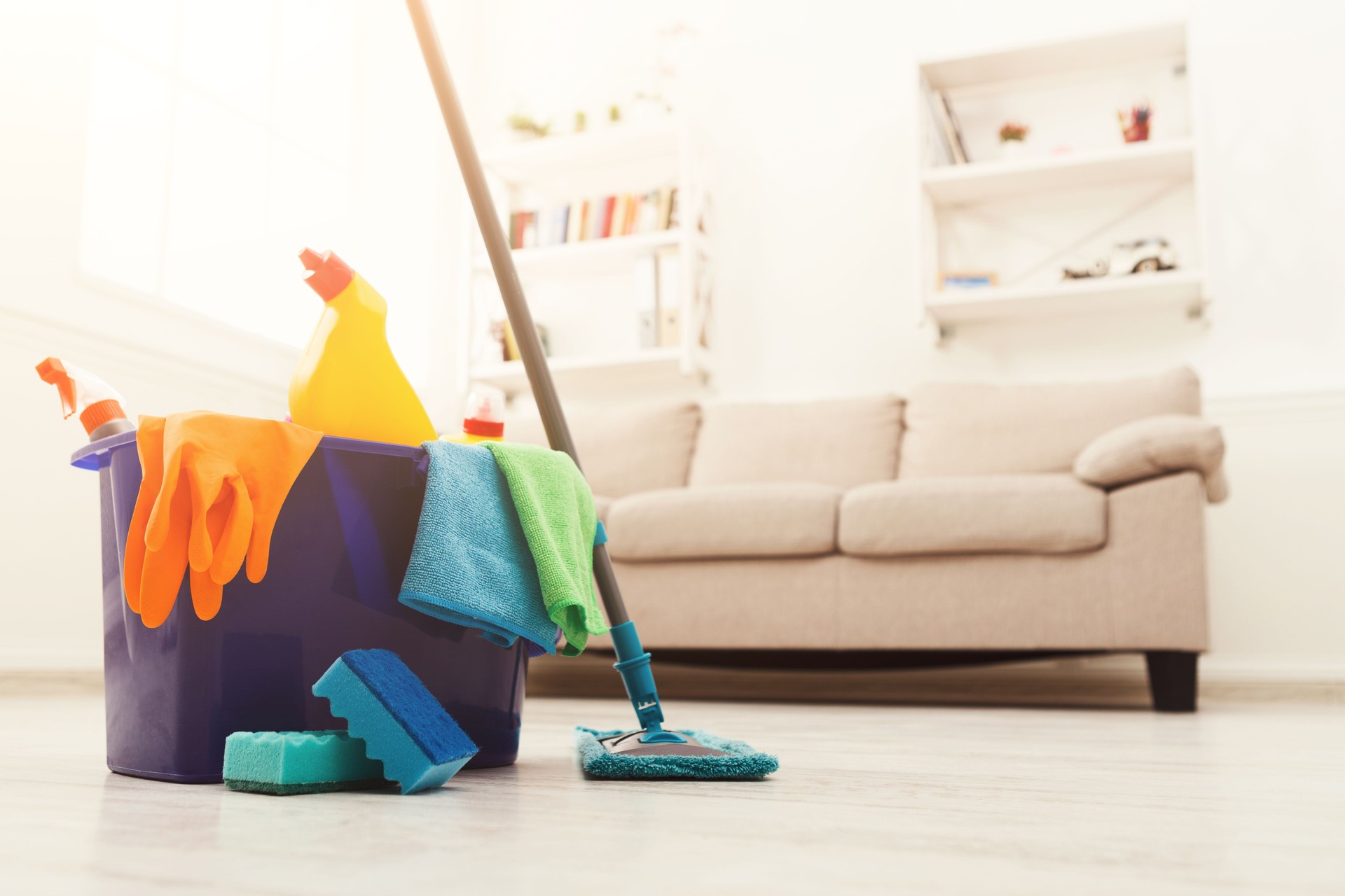 Bucket with sponges, chemicals bottles and mopping stick.